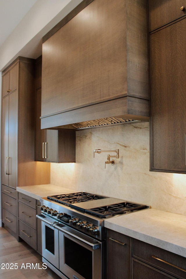 12863 E Cochise Rd, Scottsdale, AZ 85259 - kitchen with double oven range, light countertops, backsplash, dark brown cabinetry, and light wood-style flooring