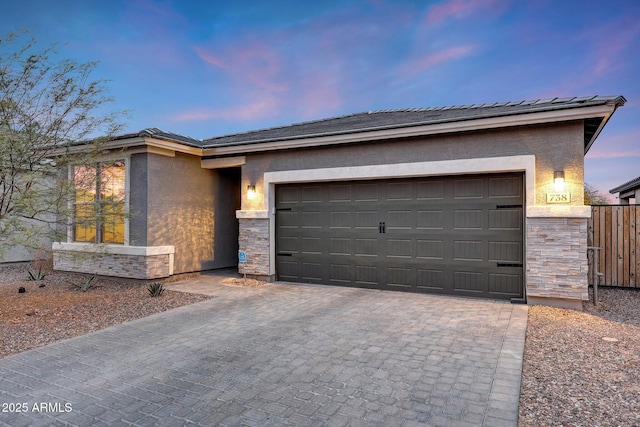 view of front of house with an attached garage, stone siding, decorative driveway, and stucco siding