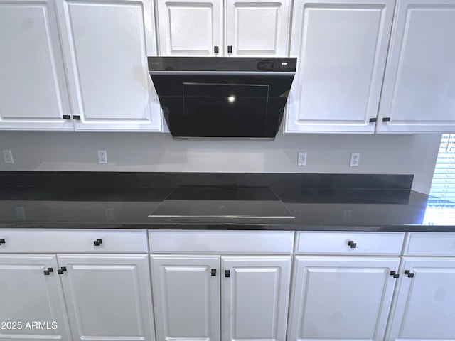 kitchen featuring black electric cooktop, exhaust hood, and white cabinets