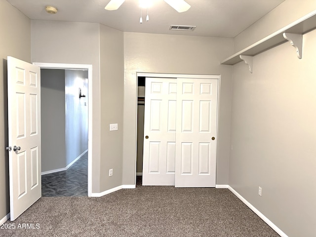 unfurnished bedroom with ceiling fan, a closet, and dark colored carpet