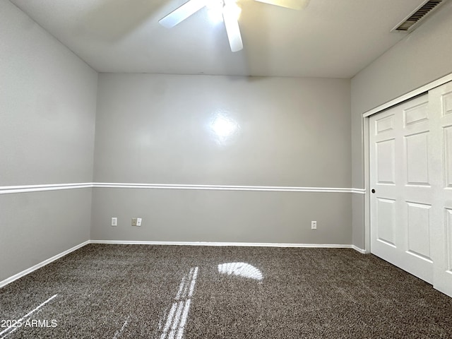 unfurnished bedroom with ceiling fan, a closet, and dark colored carpet