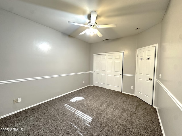 unfurnished bedroom with ceiling fan, dark carpet, and a closet