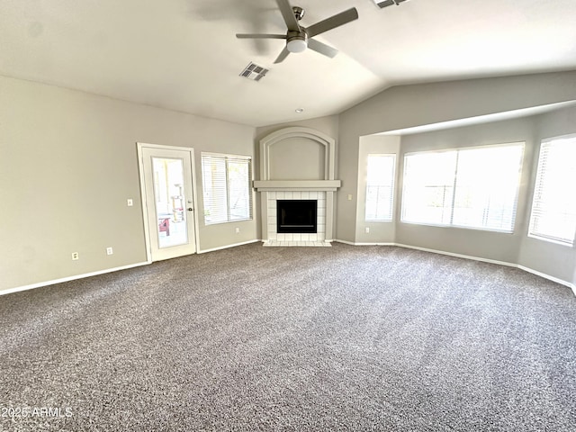 unfurnished living room featuring a tiled fireplace, lofted ceiling, and a healthy amount of sunlight