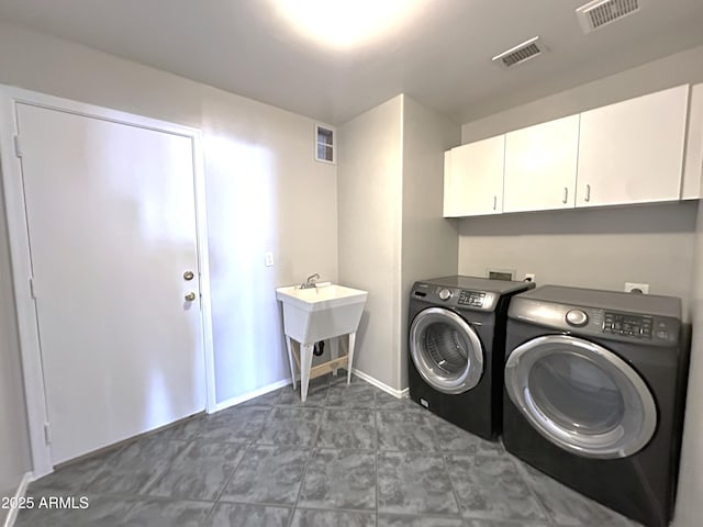 clothes washing area featuring cabinets, sink, and washing machine and clothes dryer