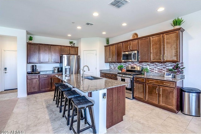 32047 N 125th Ave, Peoria, AZ 85383 - kitchen featuring appliances with stainless steel finishes, a sink, a kitchen bar, stone countertops, and a center island with sink