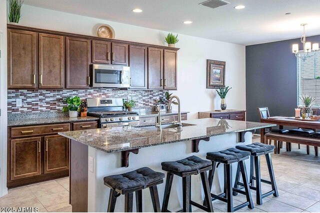 32047 N 125th Ave, Peoria, AZ 85383 - kitchen featuring stainless steel appliances, a sink, stone countertops, tasteful backsplash, and a breakfast bar