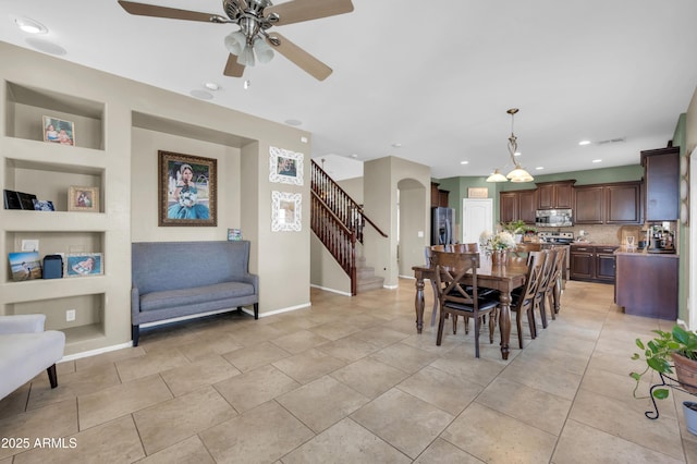 2016 S 102nd Ln, Tolleson, AZ 85353 - dining space with built in shelves, stairs, ceiling fan, baseboards, and arched walkways