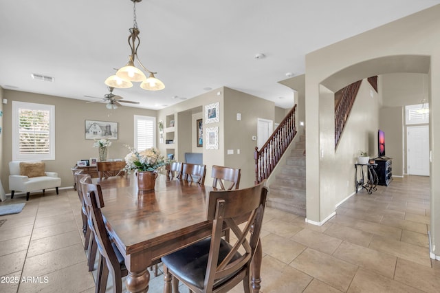 2016 S 102nd Ln, Tolleson, AZ 85353 - dining space featuring a ceiling fan, arched walkways, baseboards, stairway, and light tile patterned flooring