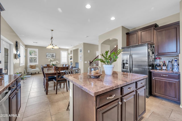 2016 S 102nd Ln, Tolleson, AZ 85353 - kitchen featuring appliances with stainless steel finishes, a kitchen island, light stone counters, open floor plan, and light tile patterned floors