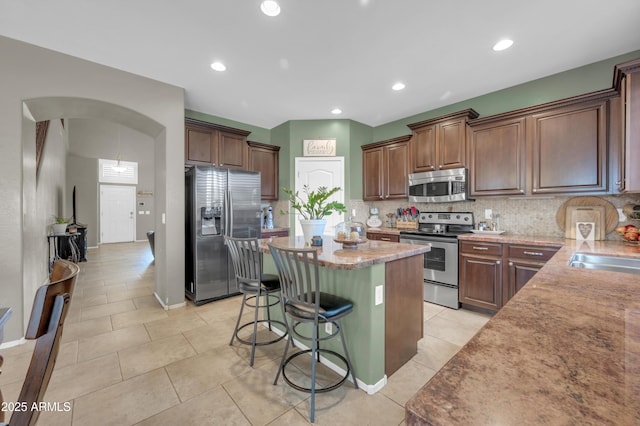 2016 S 102nd Ln, Tolleson, AZ 85353 - kitchen with appliances with stainless steel finishes, a center island, a kitchen breakfast bar, decorative backsplash, and recessed lighting