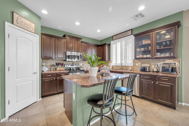 2016 S 102nd Ln, Tolleson, AZ 85353 - kitchen featuring appliances with stainless steel finishes, backsplash, a breakfast bar, dark brown cabinets, and recessed lighting