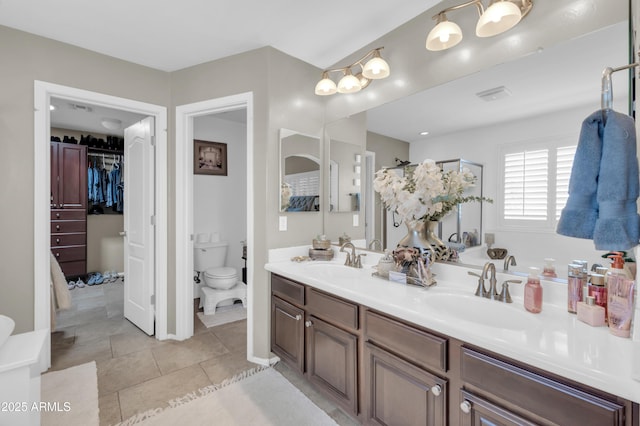 2016 S 102nd Ln, Tolleson, AZ 85353 - bathroom featuring double vanity, toilet, a walk in closet, and tile patterned flooring