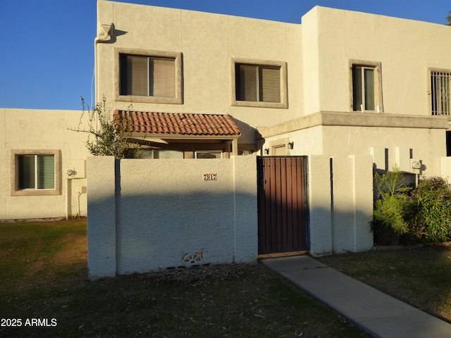 view of front of house with fence, a gate, and stucco siding