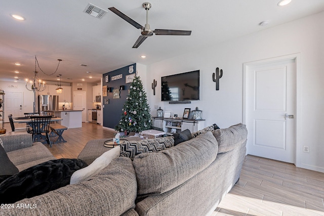 living room with sink, ceiling fan with notable chandelier, and light hardwood / wood-style flooring