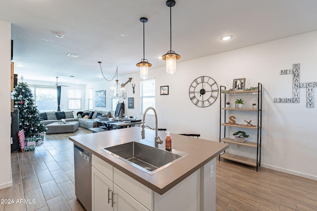 kitchen with sink, white cabinetry, stainless steel dishwasher, pendant lighting, and a kitchen island with sink