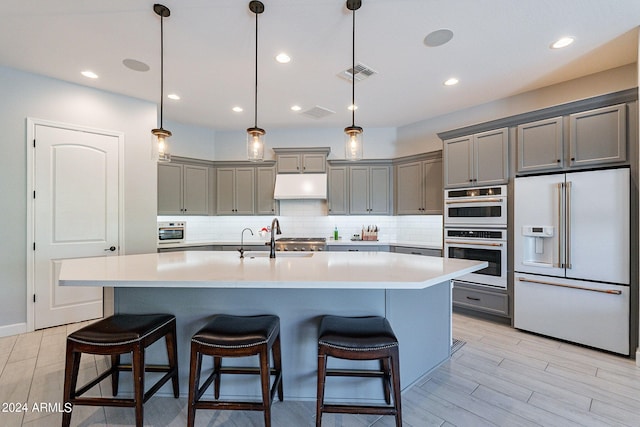 kitchen featuring hanging light fixtures, high end white refrigerator, stainless steel double oven, and backsplash