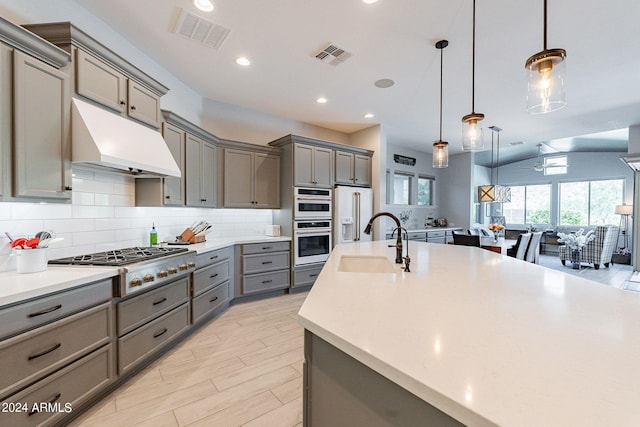 kitchen with stainless steel appliances, backsplash, pendant lighting, sink, and vaulted ceiling