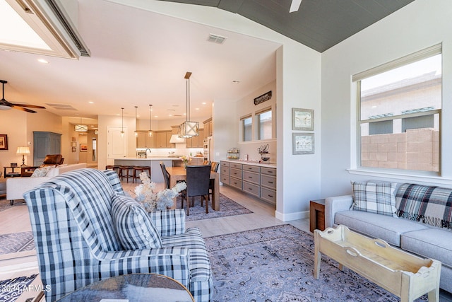 living room with ceiling fan, light hardwood / wood-style flooring, lofted ceiling, and sink