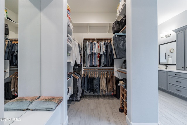 walk in closet with sink and light hardwood / wood-style flooring