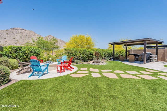 view of yard with an outdoor fire pit, a mountain view, and a patio