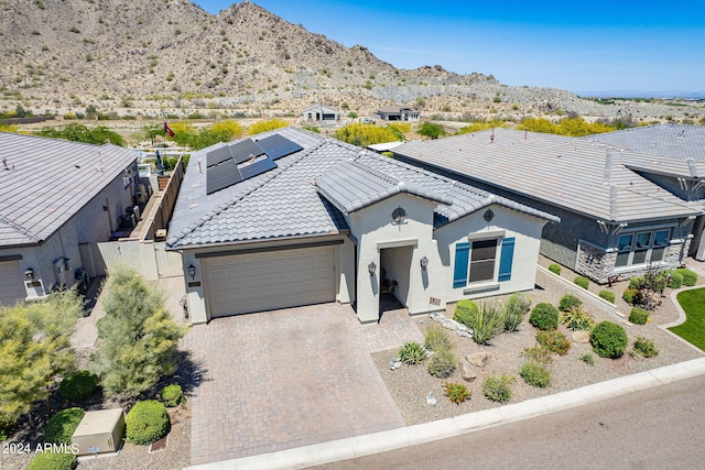 view of front of property featuring a garage, a mountain view, and solar panels