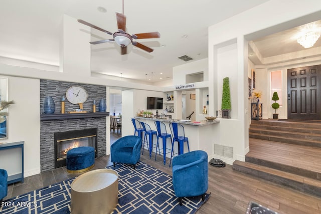 living room with a large fireplace, ceiling fan, a raised ceiling, and dark hardwood / wood-style floors