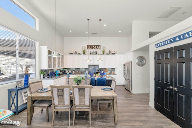 dining space featuring a high ceiling, plenty of natural light, and wood-type flooring