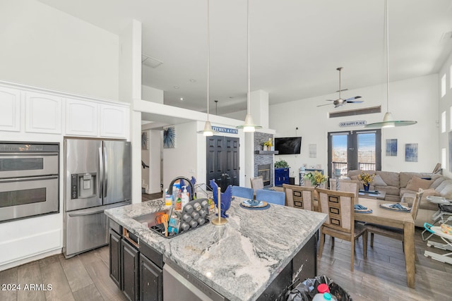 kitchen with ceiling fan, wood-type flooring, a center island, and stainless steel appliances