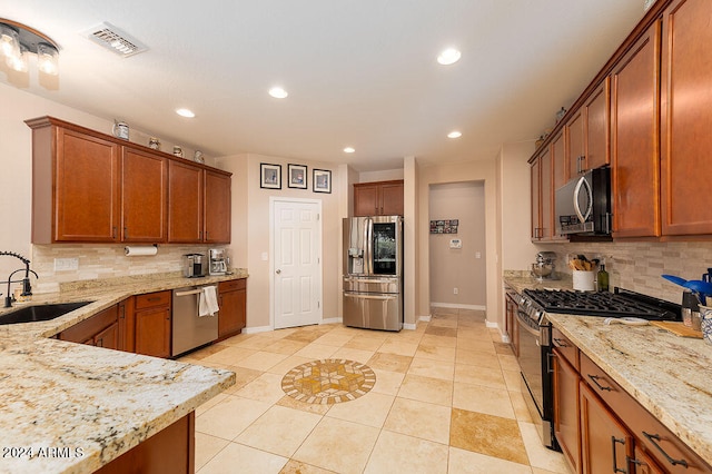 kitchen with appliances with stainless steel finishes, light stone countertops, decorative backsplash, and sink