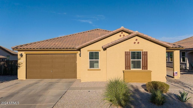 mediterranean / spanish-style house with concrete driveway, a tiled roof, a garage, and stucco siding