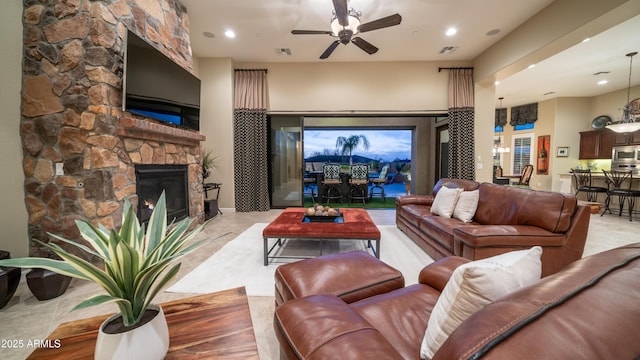 living room with ceiling fan, a stone fireplace, visible vents, and recessed lighting