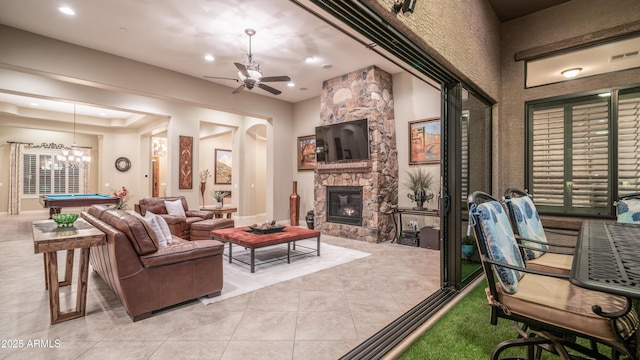 living area with light tile patterned floors, ceiling fan, arched walkways, a fireplace, and billiards