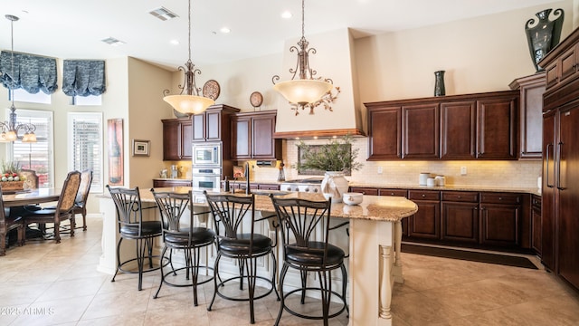 kitchen featuring built in appliances, a high ceiling, a breakfast bar area, and visible vents