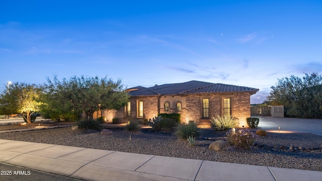 view of front of home with stone siding, driveway, and a tiled roof