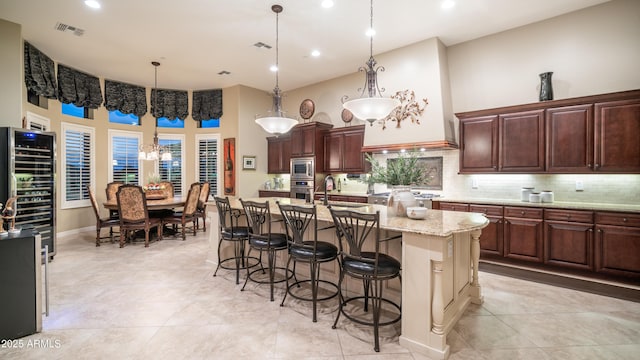 kitchen with visible vents, decorative backsplash, a high ceiling, appliances with stainless steel finishes, and a kitchen bar