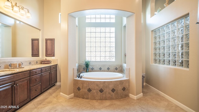 full bathroom featuring tile patterned flooring, a garden tub, vanity, and baseboards