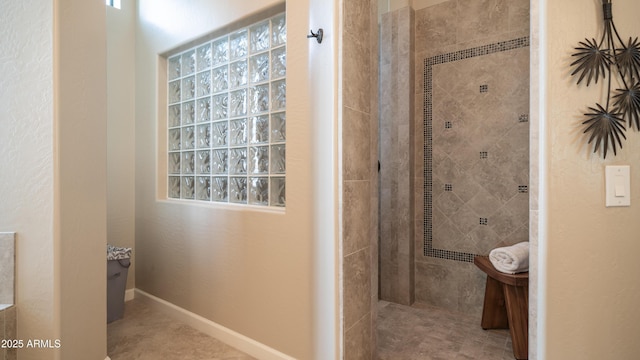 full bathroom featuring tiled shower and baseboards