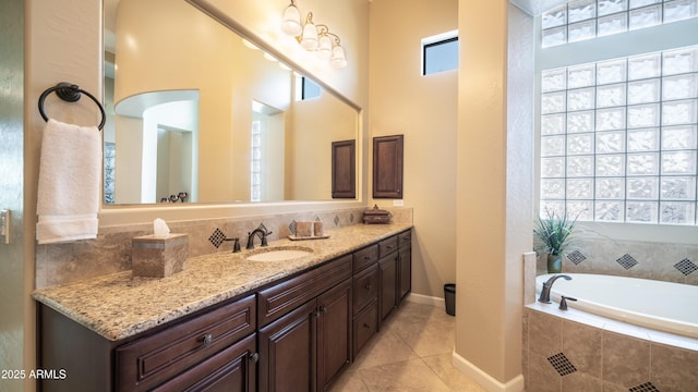 bathroom with a garden tub, vanity, baseboards, and tile patterned floors