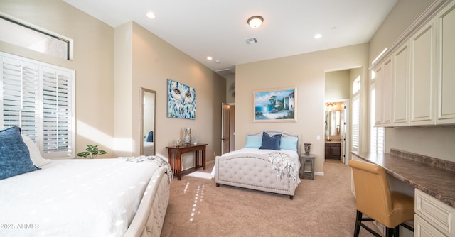 bedroom featuring light carpet, built in study area, connected bathroom, and recessed lighting