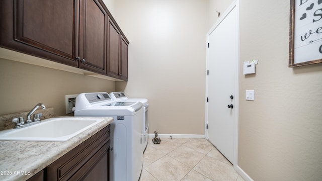 clothes washing area with light tile patterned floors, a sink, baseboards, cabinet space, and washing machine and clothes dryer