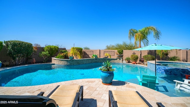 view of pool with a pool with connected hot tub, a fenced backyard, and a patio