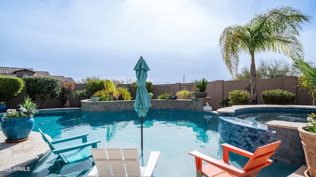 view of pool with a fenced backyard and a pool with connected hot tub