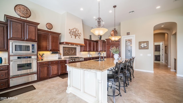 kitchen with arched walkways, a warming drawer, visible vents, appliances with stainless steel finishes, and a sink