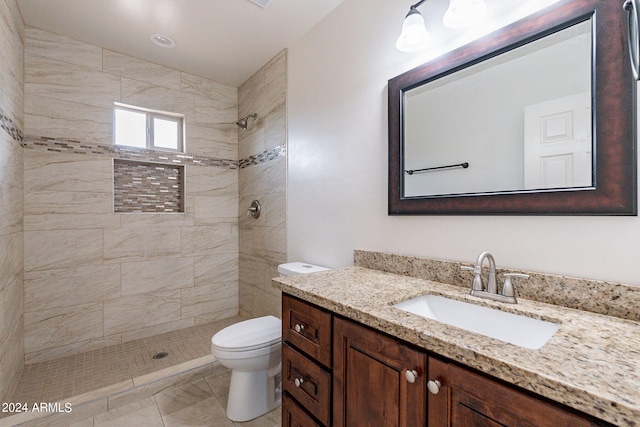 bathroom with vanity, tile patterned flooring, toilet, and tiled shower