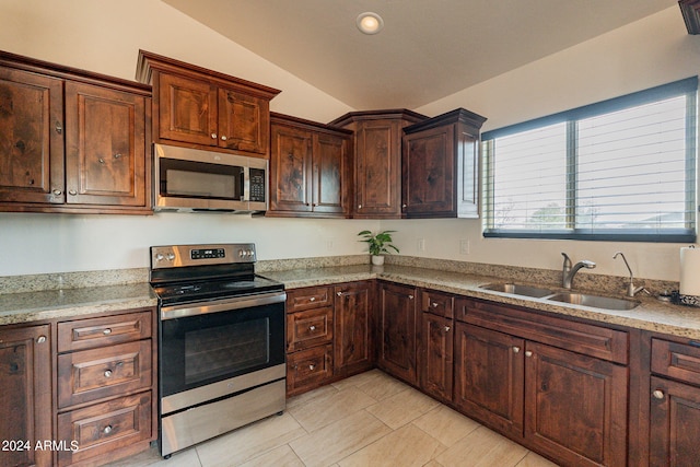 kitchen with sink, vaulted ceiling, stainless steel appliances, light tile patterned floors, and light stone countertops