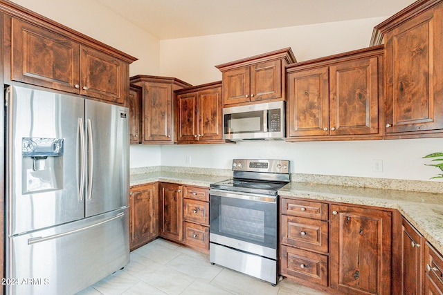 kitchen featuring vaulted ceiling, appliances with stainless steel finishes, and light stone counters