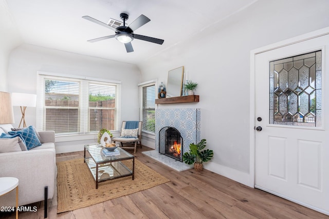 living room featuring hardwood / wood-style flooring, a tile fireplace, and ceiling fan