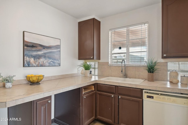 kitchen with dishwasher, dark brown cabinetry, and sink