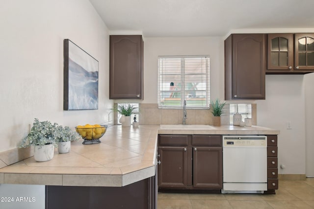 kitchen featuring dark brown cabinetry, sink, white dishwasher, and light tile patterned floors