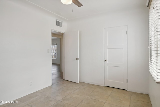 unfurnished bedroom featuring light tile patterned floors, multiple windows, and ceiling fan